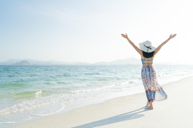 Mulher feliz usando chapéu de sol de praia e biquíni lindo curtindo praia relaxando alegre no verão