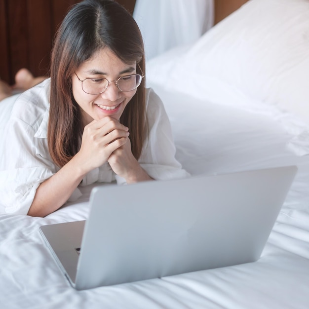 Mulher feliz usando laptop para trabalho feminino reunião on-line por notebook de computador na rede de tecnologia de cama trabalho em estilo de vida doméstico e conceito de comunicação digital