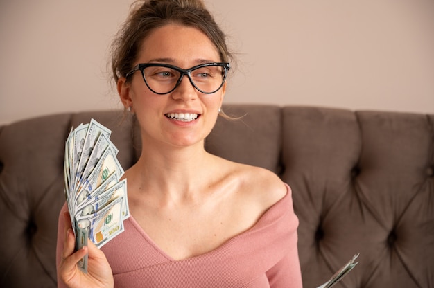 Mulher feliz usando óculos escuros, mostrando dinheiro