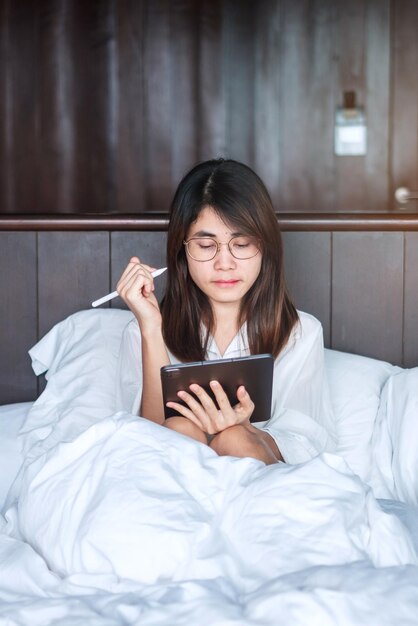 Mulher feliz usando tablet para mídia social jovem fêmea assistindo filmes no computador na cama em casa rede de tecnologia compras on-line estilo de vida de comércio eletrônico e conceito de comunicação digital