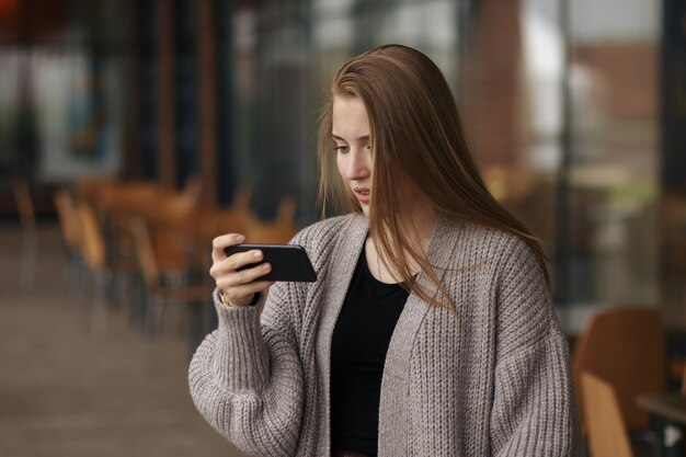 Mulher feliz usando um smartphone na rua com um fundo desfocado