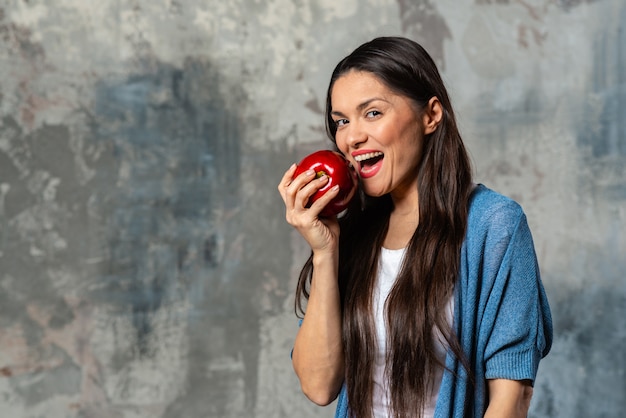 Foto mulher feliz vai morder uma grande maçã com a boca aberta.