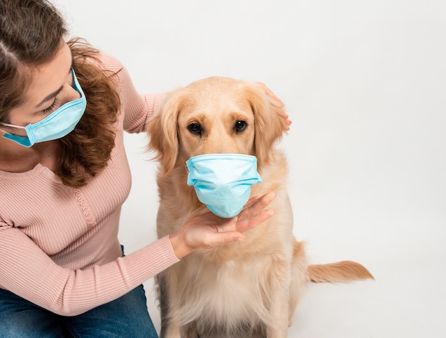 Mulher feminina em máscara facial protegida médica com cão Golden retriever em branco isolado.