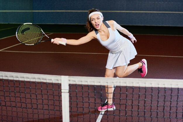Mulher feroz jogando tênis no tribunal