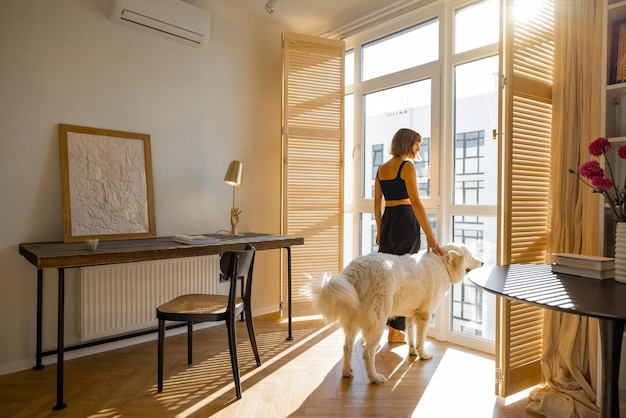 Mulher fica com cachorro pelas cortinas da janela em casa