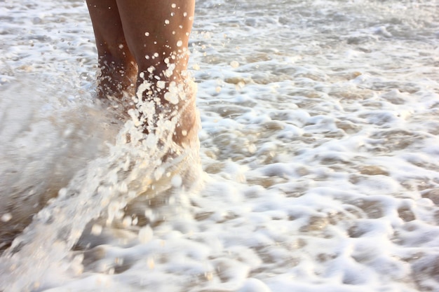 Mulher fica na praia esperando a onda impactar suas pernas