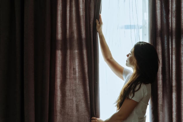 Mulher fica perto da janela na luz do sol