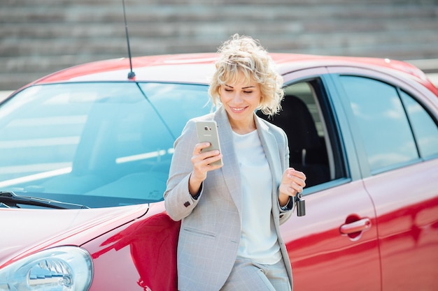 Mulher fica perto de um carro quebrado após um acidente, liga para o seguro automóvel