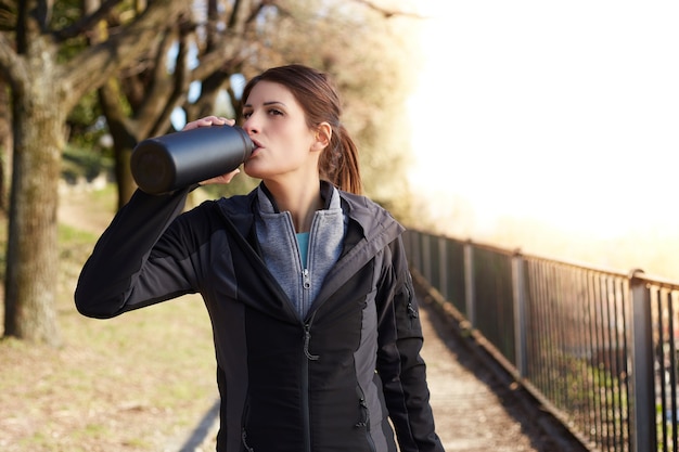 Mulher fitness bebendo água de uma garrafa após o treino