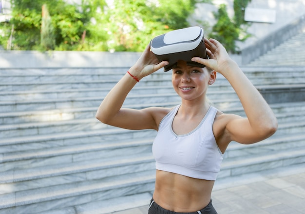 Mulher fitness com capacete de realidade virtual ao ar livre