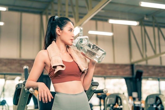 Mulher fitness descansando do exercício na academia e bebendo água da garrafa