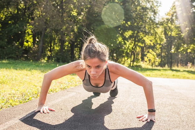 Mulher fitness fazendo flexões durante exercícios de cross training ao ar livre