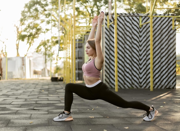 Mulher fitness praticando ioga asana poses no campo esportivo Warrior 1