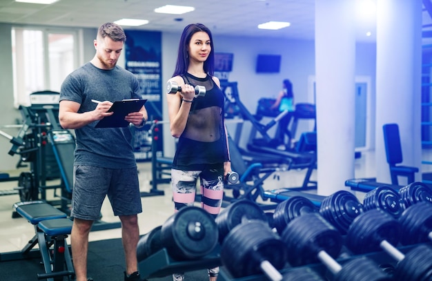 Mulher fitness se exercitando com instrutor de fitness na academia Instrutor de fitness pessoal Treinamento pessoal