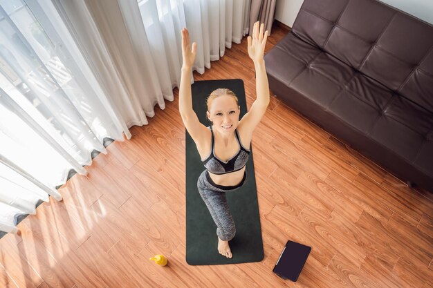 Mulher fitness se exercitando no chão em casa e assistindo a vídeos de fitness em um tablet As pessoas praticam esportes online por causa do coronovírus