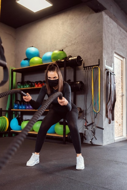 Mulher fitness usando cordas de batalha de treinamento para exercícios na academia