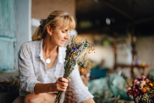 Mulher florista faz com as mãos um lindo arranjo de flores no país