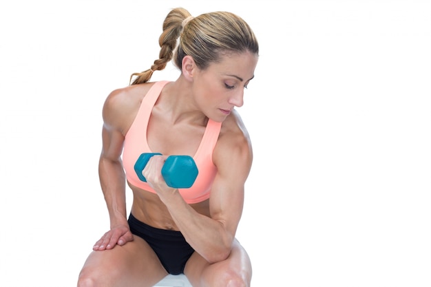 Mulher forte fazendo curvatura com bíceps com dumbbell azul