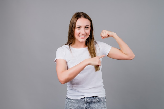 Mulher forte, mostrando o bíceps isolado em cinza