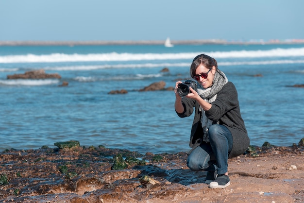 mulher fotógrafa tirando foto na praia