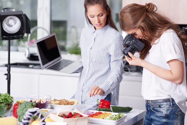 Mulher fotografando comida na cozinha