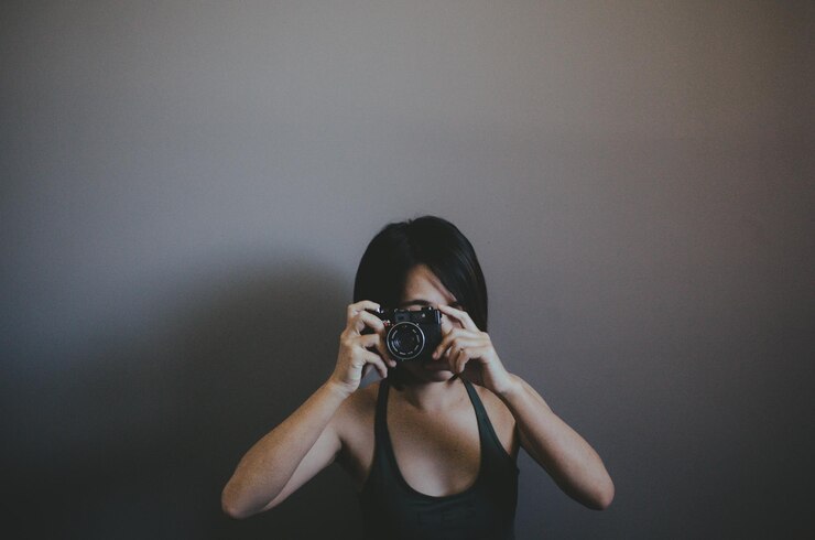 Foto mulher fotografando enquanto está de pé contra a parede