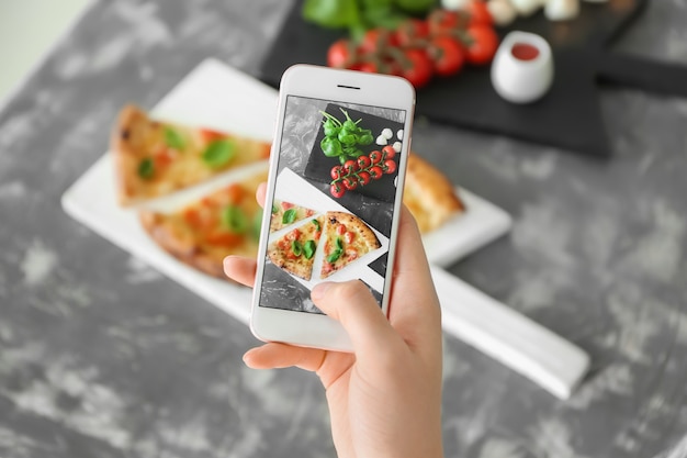 Mulher fotografando pizza deliciosa Margherita com telefone celular