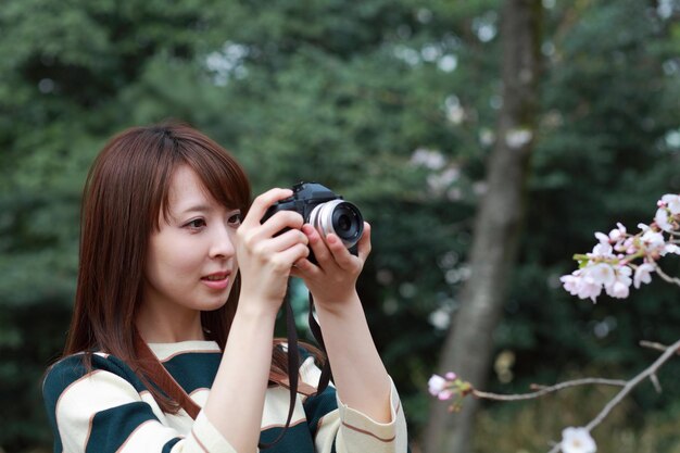 Mulher fotografando plantas com câmera digital no parque