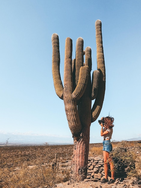 Mulher fotografando um cacto em todo o comprimento