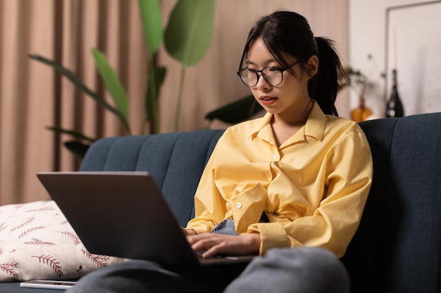 Mulher freelancer coreana usando laptop trabalhando online sentado em casa