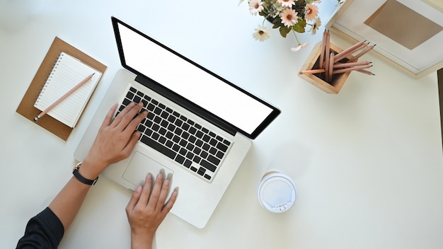 Mulher freelancer digitando maquete laptop com espaço de trabalho vista superior.