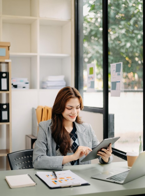 Mulher freelancer está trabalhando em seu computador tablet e laptop Fazendo relatório de análise contábil dados de investimento imobiliário Financeiro