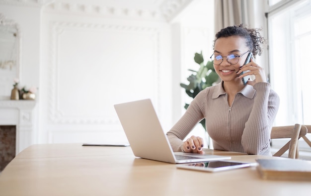 Foto mulher freelancer falando ao telefone no escritório olhando para um local de trabalho de computador portátil em um espaço de coworking