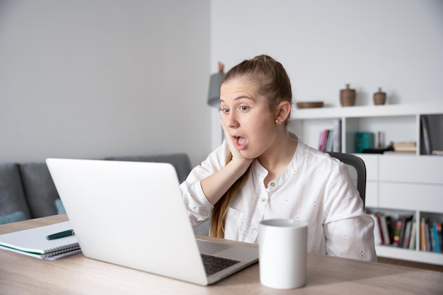 Mulher freelancer surpresa olhando para laptop