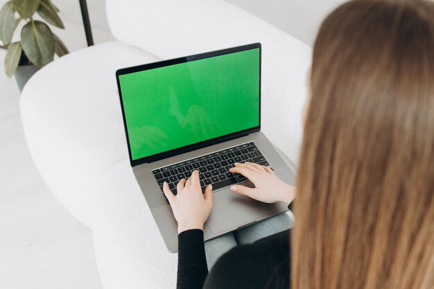 Mulher freelancer usando laptop com tela verde no monitor Conceito de trabalho remoto