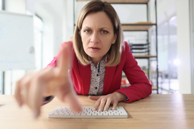 Foto mulher furiosa cutuca o dedo indicador no monitor digitando no teclado trabalhadora loira suspeita