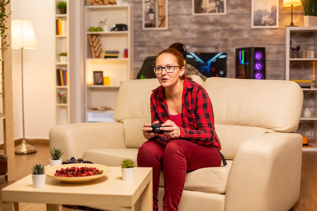 Mulher gamer jogando videogame no console da sala de estar tarde da noite
