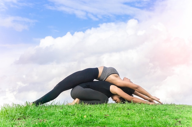 Mulher gêmea praticando ioga relaxar na natureza e céu azul de fundo