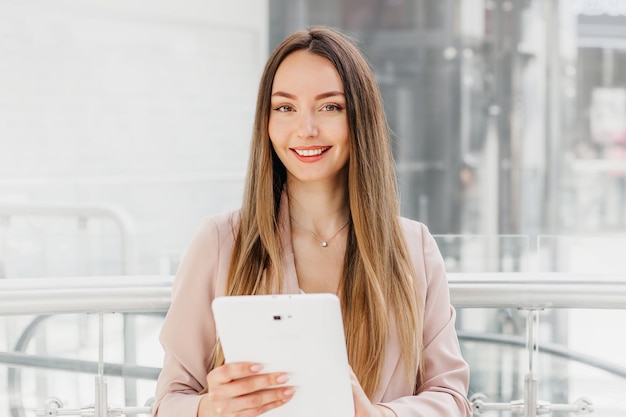 Mulher gerente de vendas segurando tablet digital em pé no centro de negócios