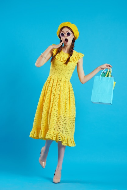 Mulher glamourosa com um chapéu amarelo, viciada em compras, de fundo estilo fashion