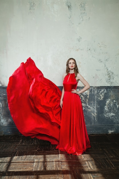 Mulher glamourosa em elegante vestido vermelho. Linda modelo em fundo retrô