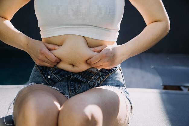 Foto mulher gorda barriga gorda gordinha obesa mulher mão segurando gordura abdominal excessiva com fita métrica mulher conceito de estilo de vida de dieta