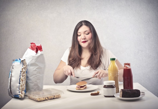 Mulher gorda comendo um hambúrguer