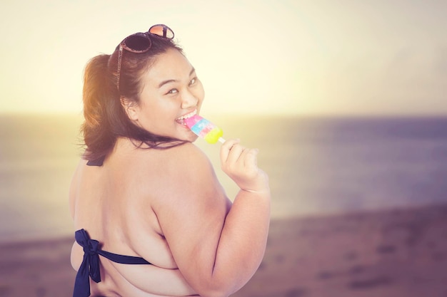 Mulher gorda feliz comendo sorvete na praia