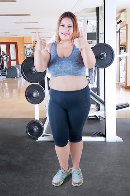 Foto mulher gorda mostra os polegares para cima no ginásio