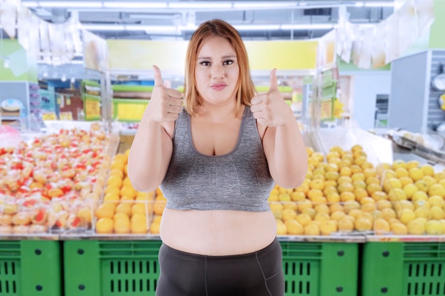 Mulher gorda mostrando polegares para cima na loja