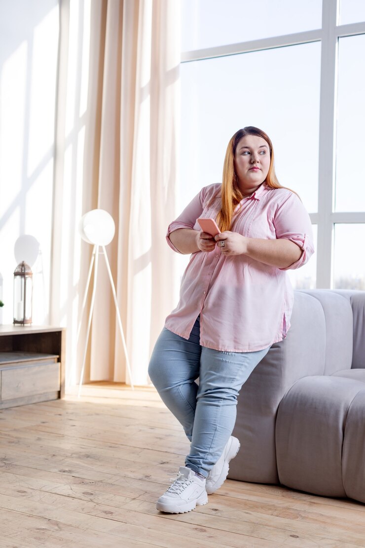 Foto mulher gordinha e bonita em pé na sala de estar olhando para o lado