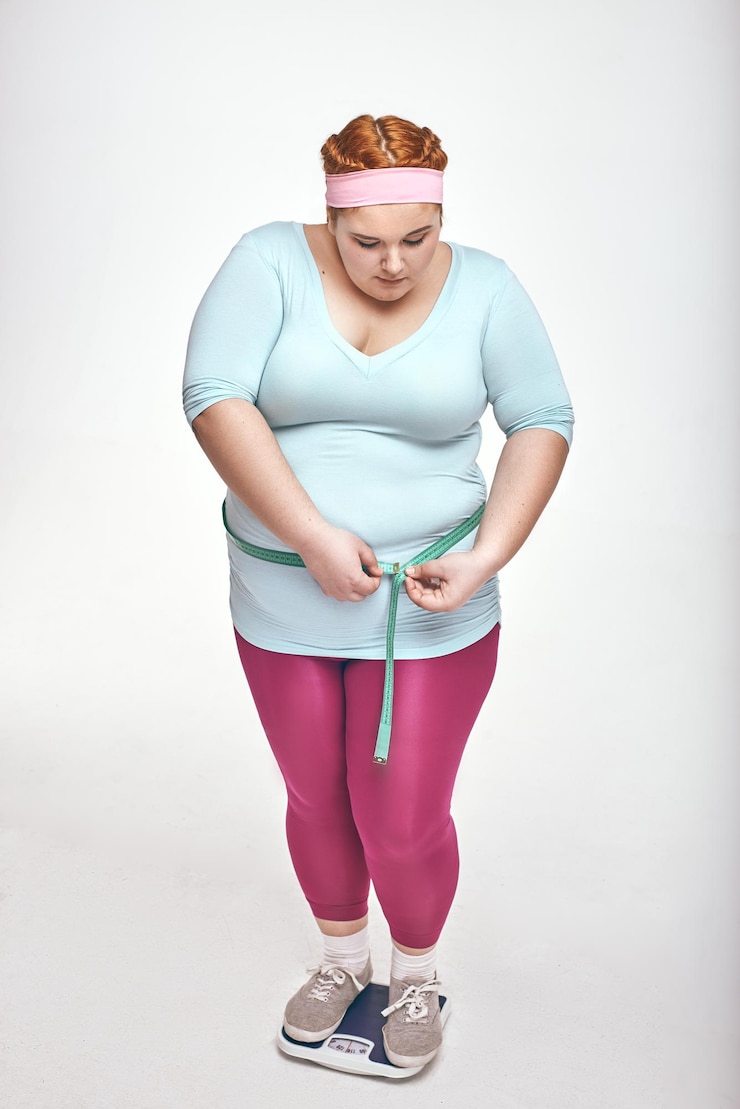 Foto mulher gordinha medindo a barriga em fundo branco
