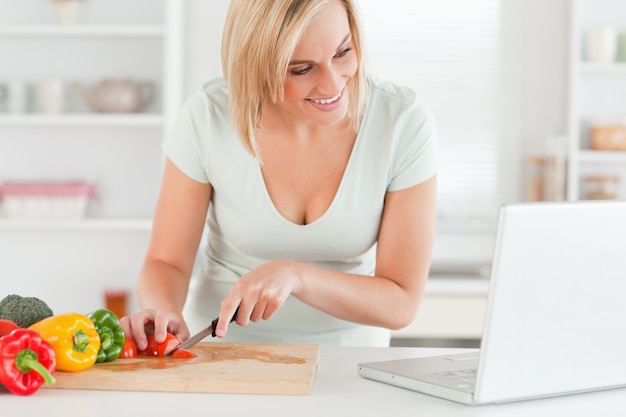 Mulher gostando de cozinhar à procura de uma receita no laptop