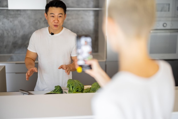 Mulher grava um vídeo no smartphone do homem cozinhar salada